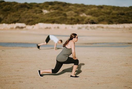 Woman doing knee exercises on a beach.