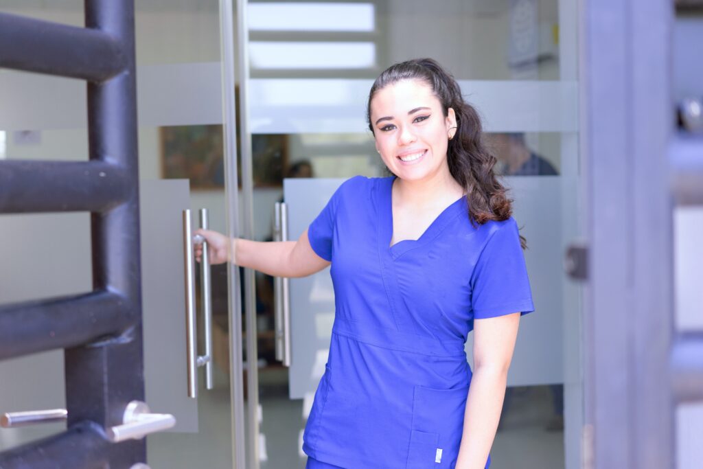 nurse smiling while holding hospital door open