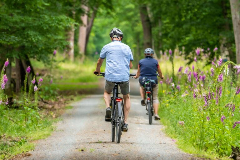 man and woman biking along forested trail