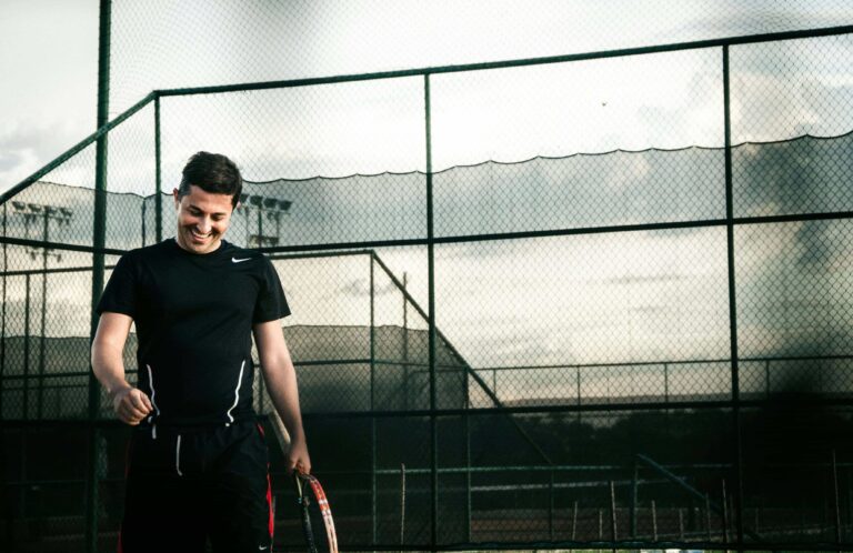 man smiles while playing tennis