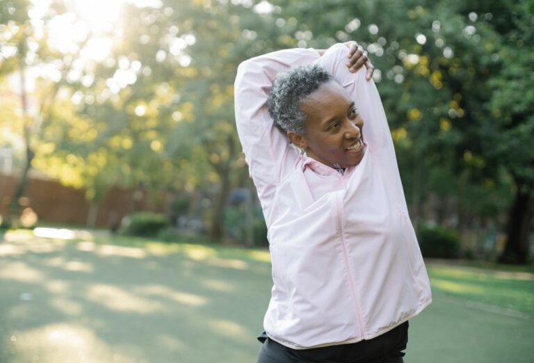 Older Woman Stretching Outdoors with a Smile on Her Face