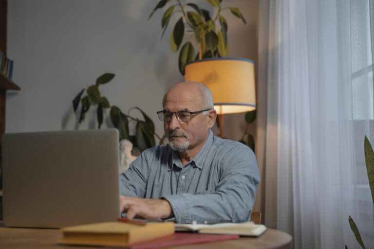 Older man using a laptop while seated at a table