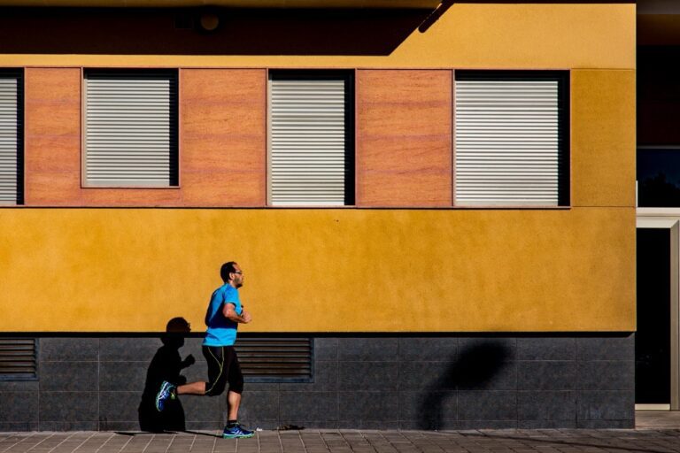 Male runner passing by a yellow building