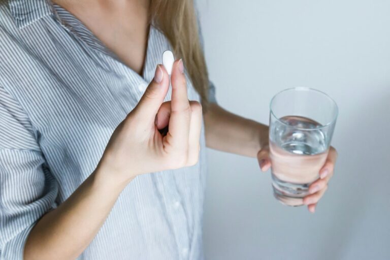 Close up of woman preparing to take a pill with a glass of water in her hand