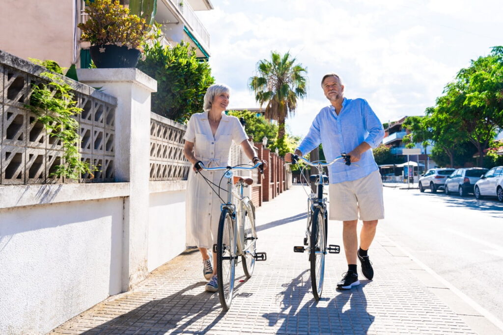 Older couple walking their bikes outdoors