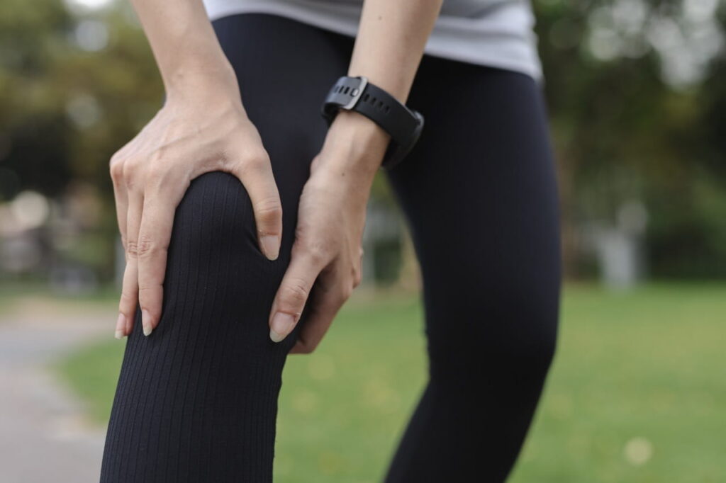 Woman grabbing at her knee during outdoor activity