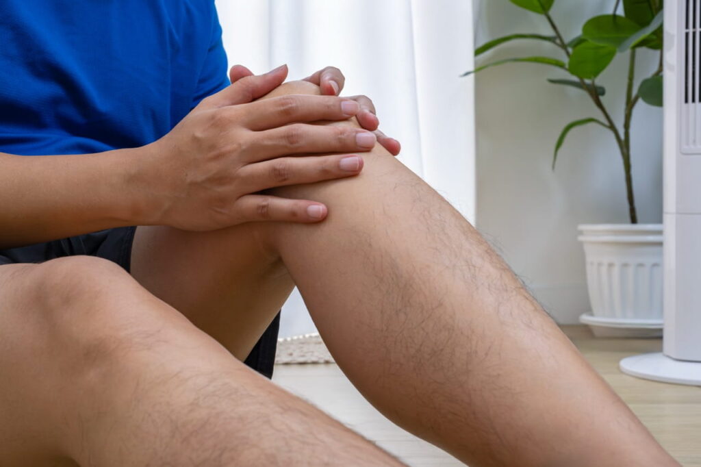 Close up of a man grabbing his knee while sitting