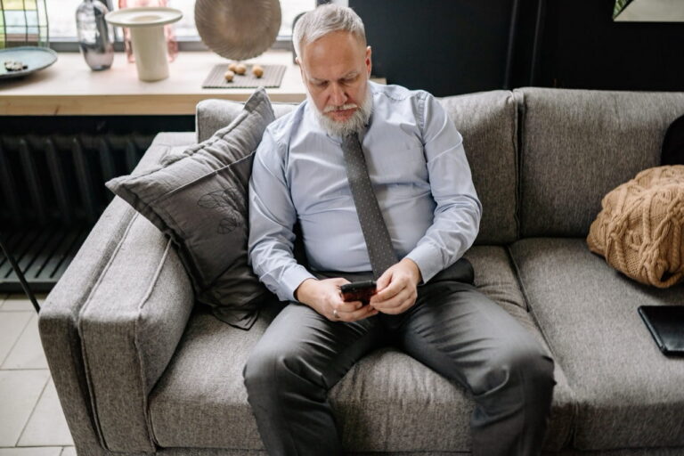 man sitting on couch looking at his phone