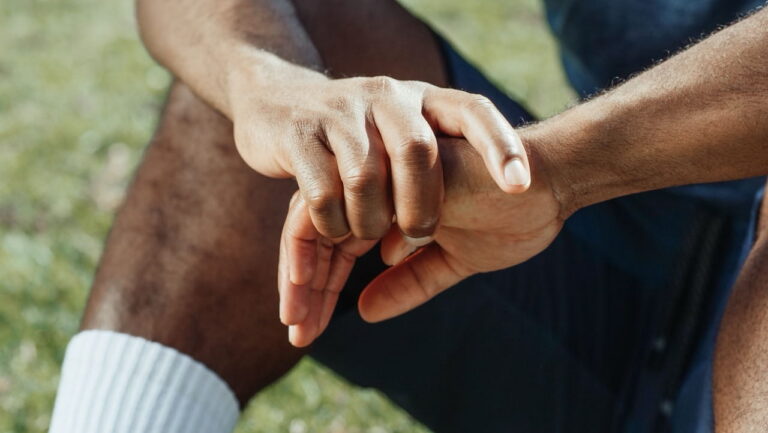 man sitting on the ground holding hands together
